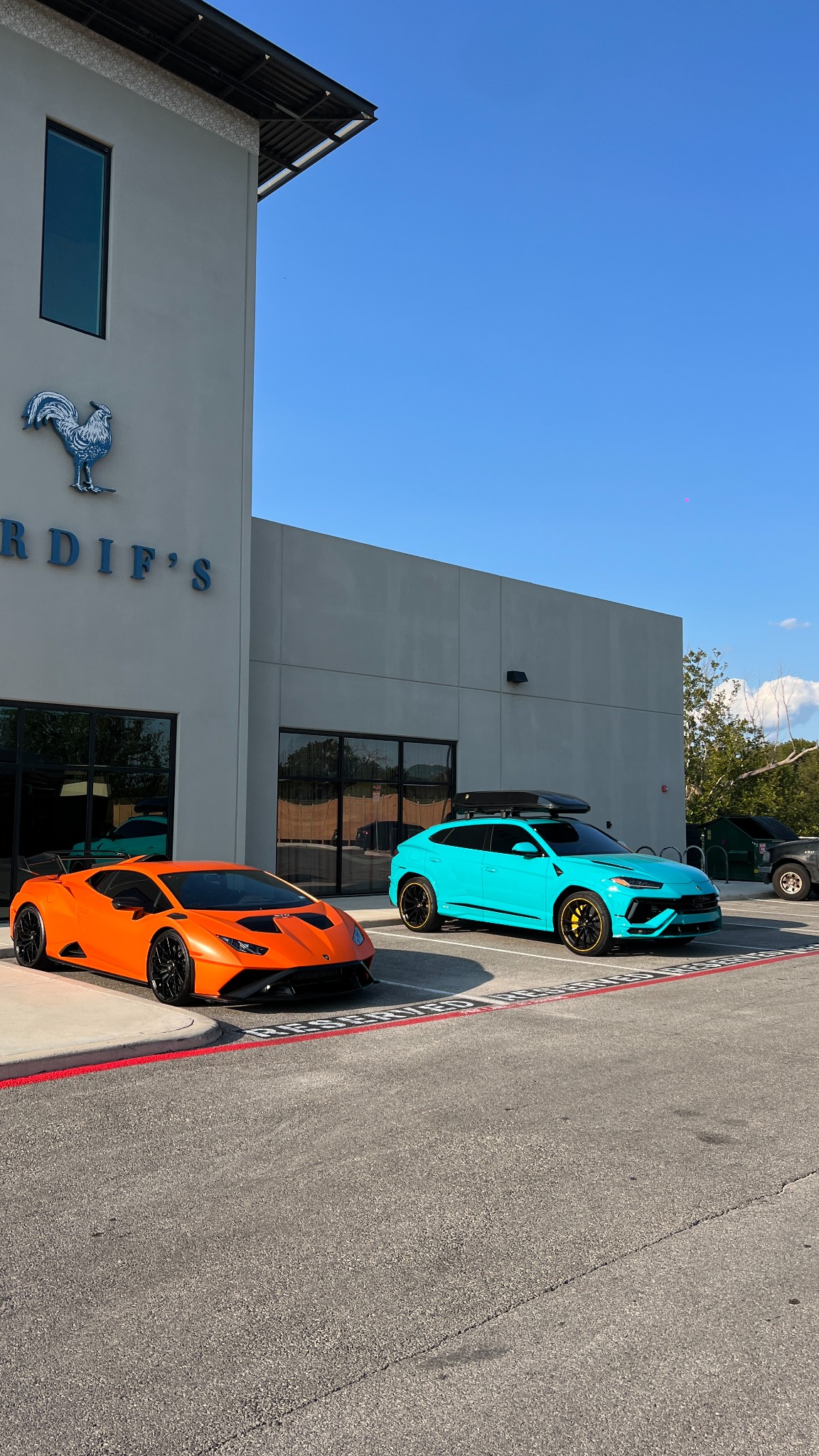 Orange Lamborghini and turquoise Lamborghini Urus with tinted windows