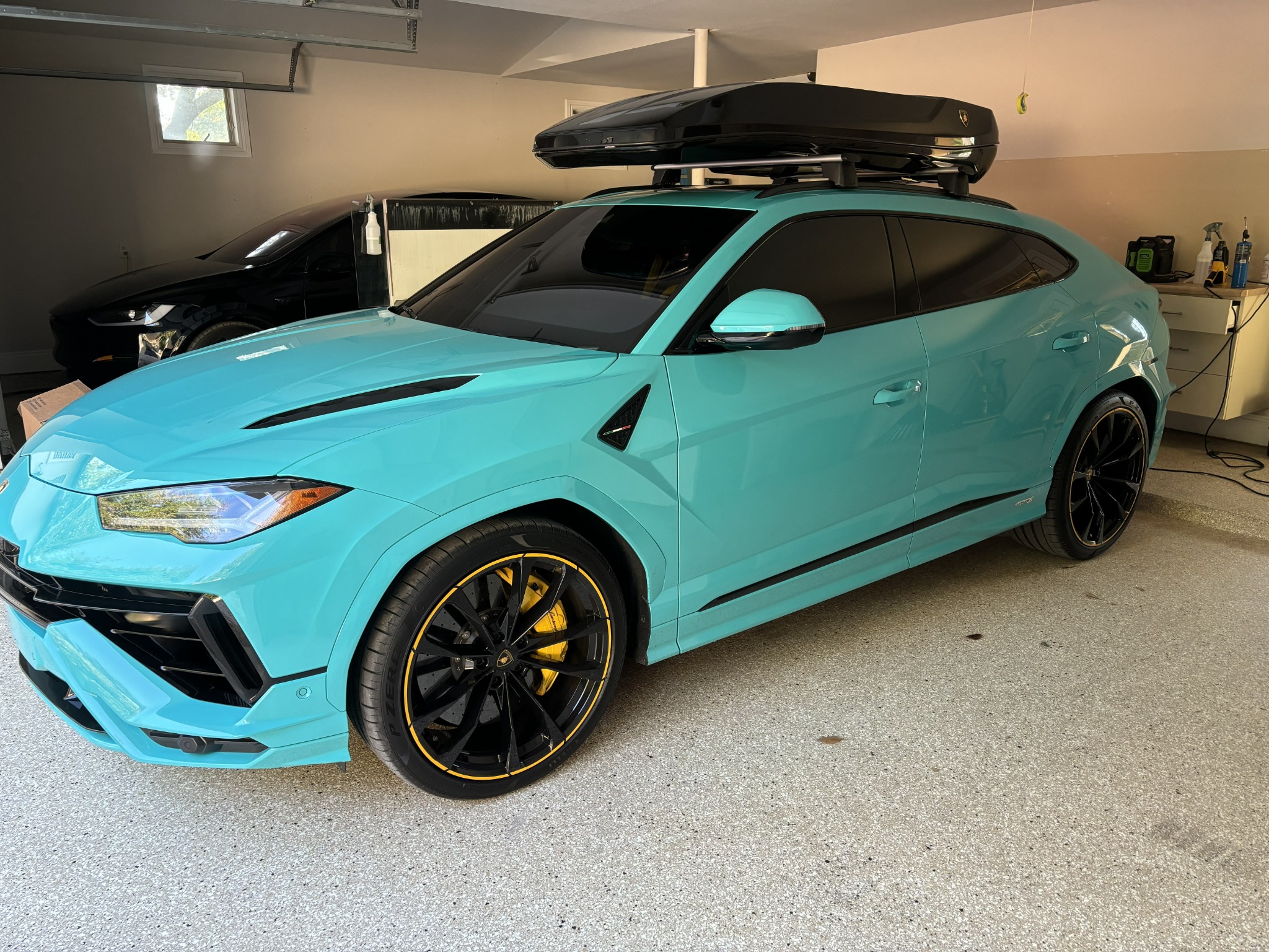 Turquoise Lamborghini Urus in garage with dark window tint